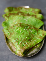 Green mint crepes on metal plate on gray background. Close up, selective focus. Gourmet breakfast. Maslenitsa. Russian thin crepes.