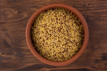 bowl of raw bulgur and quinoa on wooden table background