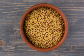 bowl of raw bulgur and quinoa on wooden table background
