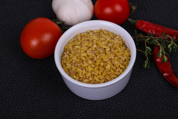 Raw bulgur in the bowl with tomatoes and garlic