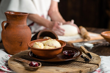 Ukrainian dumplings on a wooden board on the background of the hands of a baker