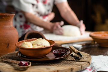 Ukrainian dumplings on a wooden board on the background of the hands of a baker