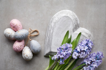 Easter flat lay with blue hyacinth flowers, easter eggs and large heart on light background