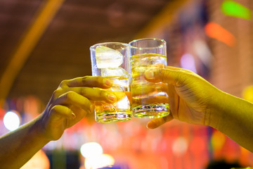 Cheers clinking of friends with whisky drink in party evening after work