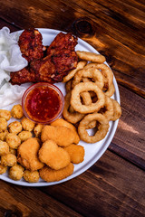 Assortment of fried snacks Onion rings, chicken wings with sauce
