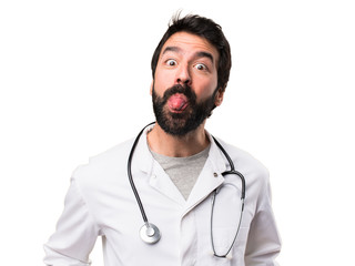 Young doctor taking out his tongue on white background