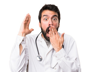 Young doctor making surprise gesture on white background