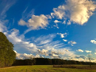 Fototapeta na wymiar Clouds over a country field with raidiating wisps.