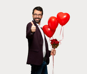 Man in valentine day giving a thumbs up gesture because something good has happened over isolated grey background