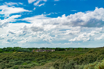 Fototapeta na wymiar View of the houses of a small town amidst beautiful coastal vegetation and blue sky with clouds in the north of france.