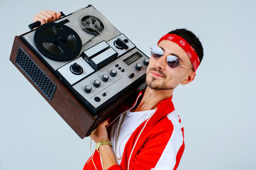cheerful fashionable man wearing a red sports suit dancing jumps with a retro tape recorder....
