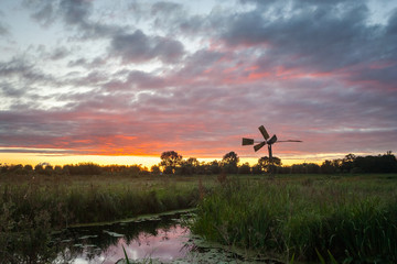 Fototapeta na wymiar Colorful sunset with old pumping mill in the countryside of Holland