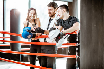 Young active friends having fun, standing together after the training on the boxing ring at the gym
