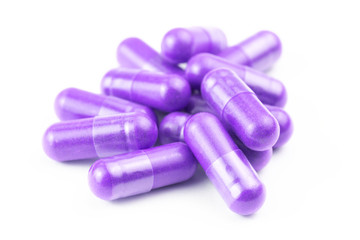 pile of proton purple color organic capsules isolated on white background closeup with selective...