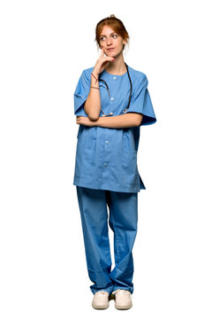 A full-length shot of a Young redhead nurse thinking an idea while looking up over isolated white background