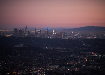 Dramatic dark pink sunset over Los Angeles skyline with city lights