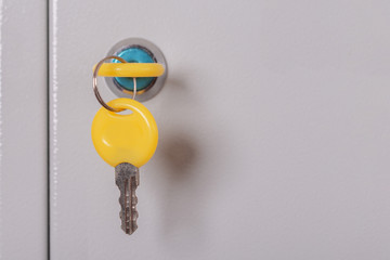 Yellow locker key close up .Keys stuck in a lock.Metal gray locker storage.Selective focus.Concept...