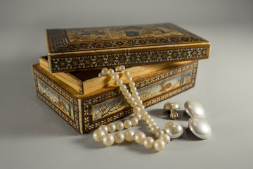 Old wooden jewel case with beautiful ornaments,  white pearl ear clips and necklace