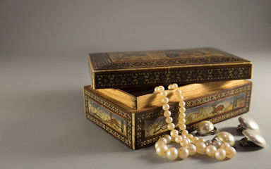 Old wooden jewel case with beautiful ornaments,  white pearl ear clips and necklace