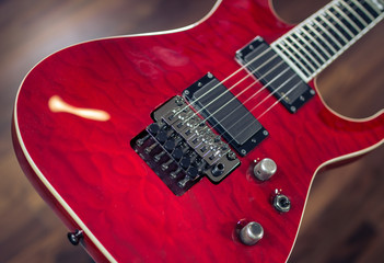 Fototapeta na wymiar Electric guitar, red colour close up with wooden soft background