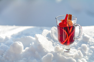 Cup with delicious mulled wine and spices on a snow covered