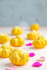 Profiteroles with cream on pink or peach color concrete surface