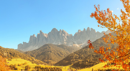 Funes Valley in Italian Dolomites Alps with yellow tree at the foreground. Travel in European Alps at autumn time. - obrazy, fototapety, plakaty