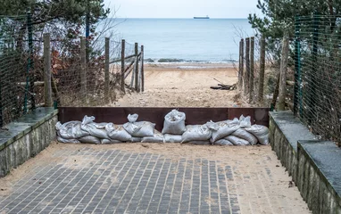 Fotobehang Entry to public beach closed and barricade with sand bags to avoid flood due to heavy storm. © Jarek Fethke