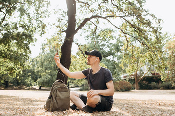 A young guy or student talking on a cell phone via video connection or listening to music or...