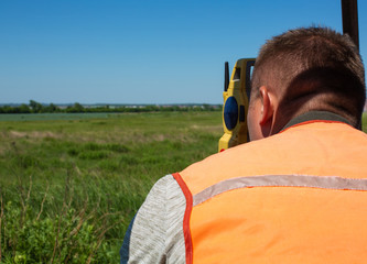 Professional Male Land Surveyor with Theodolite..Surveyor Engineer Working with Theodolite on a Green Field.