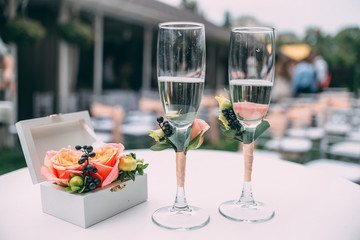 Two wedding glasses and bridal bouquet on stone in summer garden