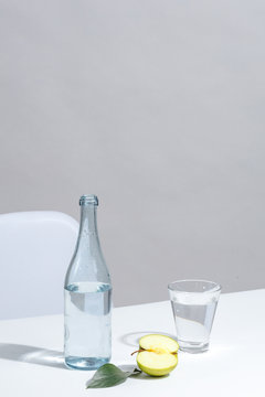 A bottle of water, a glass and a green apple on a blue background. Minimalistic concept.