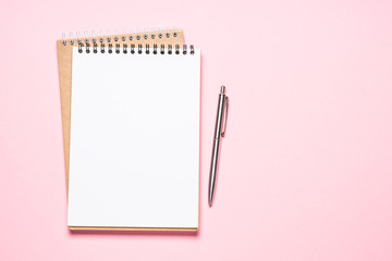 Empty notepad and pen on pink top view.