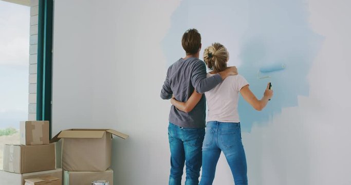 Cute couple painting wall in new home together, happy new homeowners, home painting