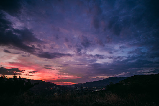Dramatic pink and purple cloudy sunset with blue sky over mountain silhouette