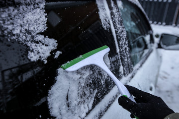 Krasnodar, Russia-December 26, 2018. Cleaning the car from the snow with a plastic scraper. Extreme snowfall in european city