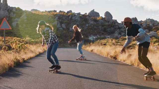 happy multi ethnic friends longboarding together riding skateboard cruising on countryside road having fun hanging out enjoying relaxed summer vacation