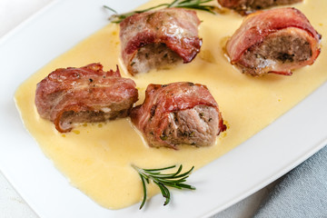 Baked pork tenderloin wrapped in bacon and served in a cheese sauce with rosemary