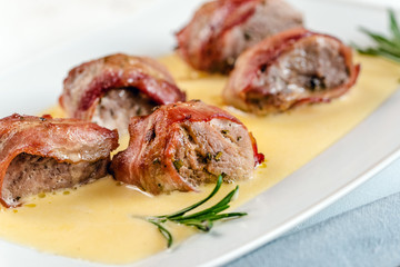 Baked pork tenderloin wrapped in bacon and served in a cheese sauce with rosemary