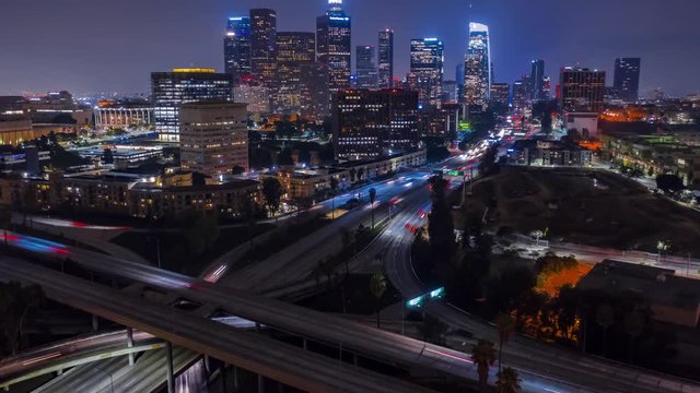 Aerial evening timelapse in motion (hyperlapse) facing downtown Los Angeles at night with traffic on a busy freeway below.