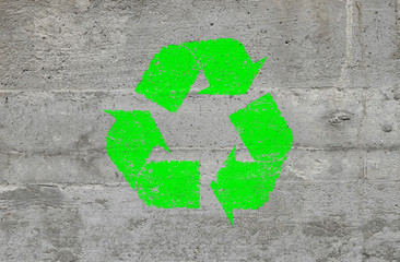 Concrete wall with green recycling logo sign