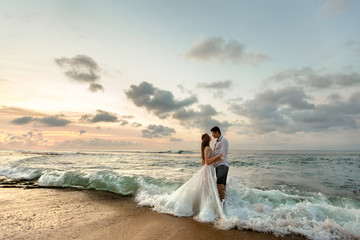 Bride and groom hugging on the beach standing in the sea water
