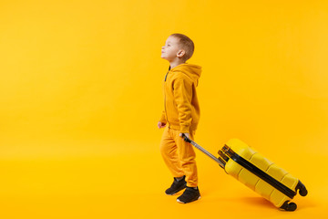 Little traveler tourist kid boy 3-4 years old isolated on yellow orange wall background studio. Passenger traveling abroad to travel on weekends getaway. Air flight journey concept. Mock up copy space