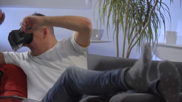 man in white shirt enjoying vr on sofa virtual reality googles 
