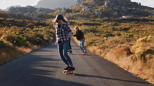 happy multi ethnic friends longboarding together riding skateboard cruising on countryside road having fun hanging out enjoying relaxed summer vacation