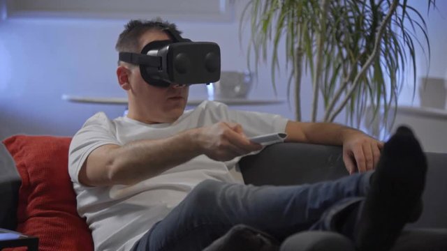 man in white shirt enjoying vr on sofa virtual reality googles 
