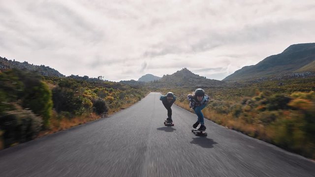 young woman longboarding overtaking in competitive race cruising on countryside road friends skating together riding skateboard wearing protective helmet