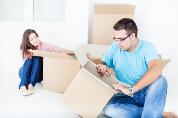 Fototapeta na wymiar Young couple unpacking cardboard boxes in new home