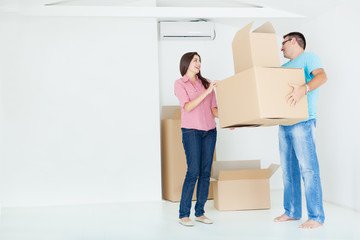 Fototapeta na wymiar Portrait of beautiful, excited woman and man holding unpacking cardboard boxes in new home,copy space