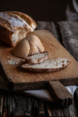 Fresh bread slice and cutting knife on rustic table